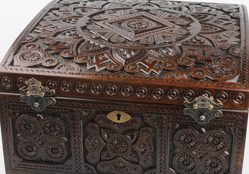 May include: A dark brown wooden box with intricate carvings and brass hinges. The box has a keyhole and a decorative design on the lid.