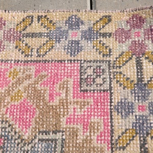 K&ouml;nnte beinhalten: Nahaufnahme eines gewebten Teppichs mit einem geometrischen Muster in Rosa-, Braun- und Graut&ouml;nen. Der Teppich hat einen Fransenrand.