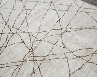 Può includere: Un tappeto bianco con un motivo geometrico marrone. Il motivo assomiglia a una rete di linee e crepe.