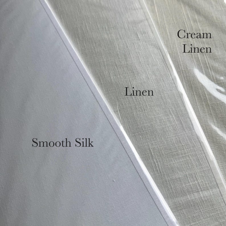 K&ouml;nnte beinhalten: Drei Stoffmuster nebeneinander, beschriftet mit Smooth Silk, Linen und Cream Linen. Die glatte Seide ist einfarbig wei&szlig;, w&auml;hrend das Leinen und das cremefarbene Leinen eine sichtbare Webstruktur in hellgrauen bzw. cremewei&szlig;en T&ouml;nen aufweisen.