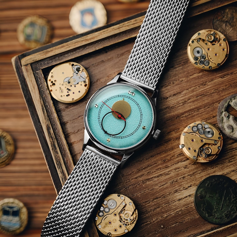 Op de afbeelding: Een set van drie keramische nestkommen in blauwe, groene en witte tinten. De kommen hebben een gespikkelde glazuur en een eenvoudig, modern ontwerp. De grootste kom heeft een diameter van ongeveer 15 cm.