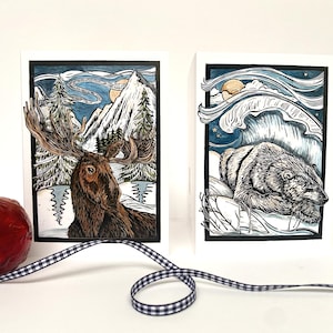 Paquete de ocho tarjetas navideñas, 2 diseños con un alce y un oso polar.