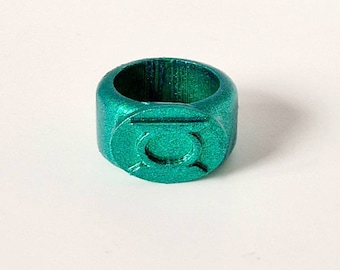 Può includere: Un anello di plastica verde con un simbolo verde in rilievo sul davanti. Il simbolo è un cerchio con una linea che lo attraversa.