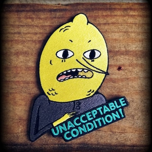May include: A yellow lemon-shaped character with a frowning face and a black eye patch. The character is wearing a dark grey shirt and holding a green sign that says "UNACCEPTABLE CONDITION!"