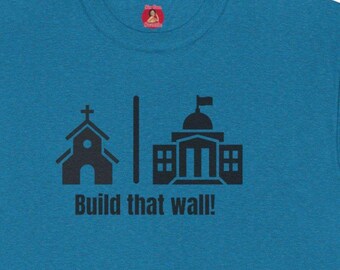 May include: A teal blue t-shirt with a black graphic of a church, a wall, and a building with a flag on top. The text "Build that wall!" is printed below the graphic.