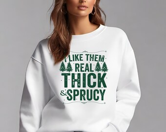 Può includere: Felpa bianca con la scritta verde "I like them real thick & sprucy". Il design include alberi di Natale verdi. La felpa è uno stile girocollo.