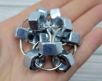 May include: A collection of silver metal hex nuts, joined by small silver rings, forming a distinctive, geometric shape. The nuts are arranged in a spherical pattern, creating an interesting industrial design.