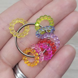 May include: A colorful keychain featuring multiple rings of translucent beads in yellow, green, blue, red, pink, and orange. The beads are strung together to form small circles, attached to a silver-colored metal ring.