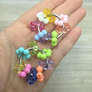 May include: Two circular metal rings decorated with clusters of small, colorful, translucent and opaque plastic beads. The beads feature a variety of bright colors including yellow, pink, blue, green, orange, and purple, arranged in small groupings around the silver-toned metal hoops.