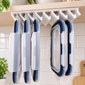 May include: A white plastic under-shelf storage rack mounted to the underside of a wooden shelf. The rack features multiple vertical slots designed to hold rectangular food container lids with dark blue silicone seals in a hanging position.