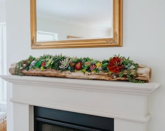May include: A long, cylindrical piece of natural driftwood serves as a planter for a dense arrangement of colorful artificial succulents. The plants feature various shades of green, red, and yellow, with trailing vines hanging over the edges.