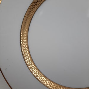 Puede incluir: Un plato de cer&aacute;mica blanco con un borde dorado y un patr&oacute;n geom&eacute;trico. El plato es perfecto para servir una variedad de platos.
