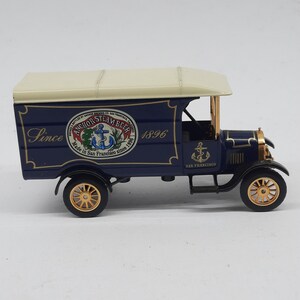 May include: A dark blue vintage-style delivery truck model with a cream-colored roof. The side features the text "Since 1896" and a circular logo reading "Anchor Steam Beer Made in San Francisco since 1896" with an anchor graphic and gold wheels.
