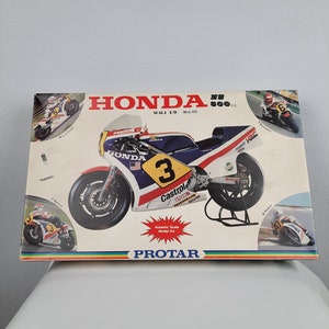 Puede incluir: Una caja de maqueta para una motocicleta Honda NS 500cc. La caja presenta una motocicleta roja, blanca y azul con el número 3 en el lateral. La caja también incluye el texto "Protar" y "Autentic Scale Model Kit".