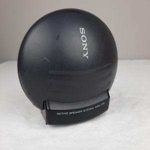 以下が含まれることがあります： 黒いソニーのアクティブスピーカーシステム、モデルSRS-T10。スピーカーは丸型で、前面に銀色のソニーロゴがあります。