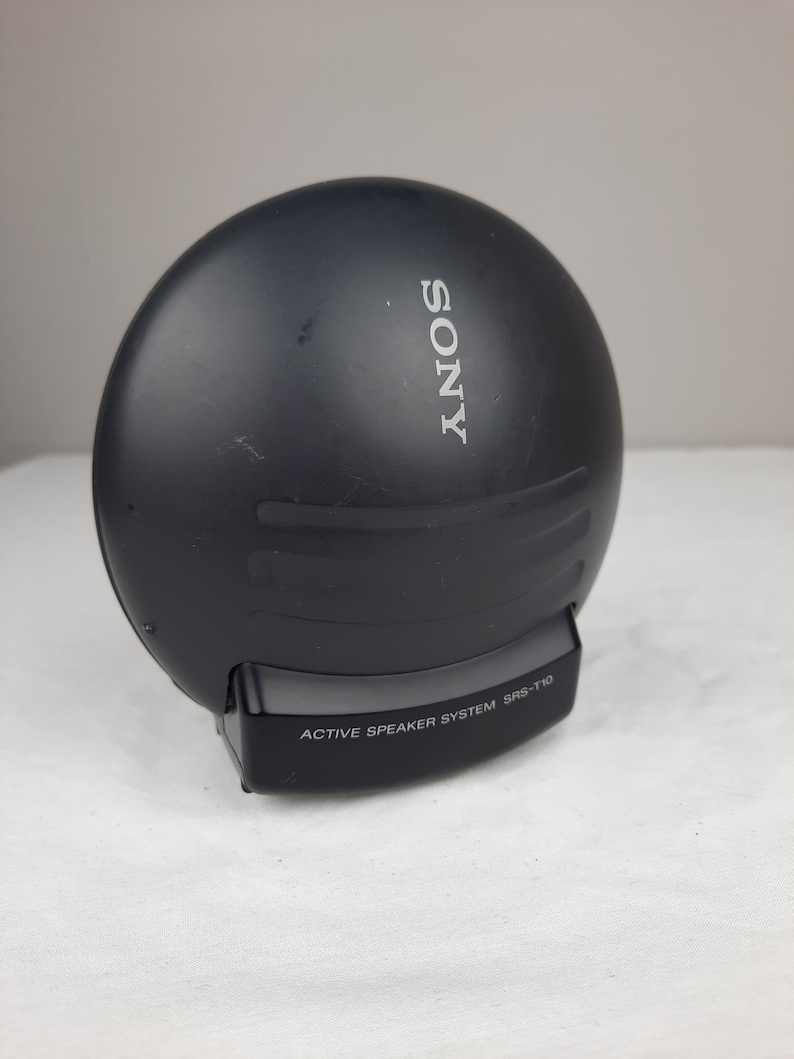 以下が含まれることがあります： 黒いソニーのアクティブスピーカーシステム、モデルSRS-T10。スピーカーは丸型で、前面に銀色のソニーロゴがあります。