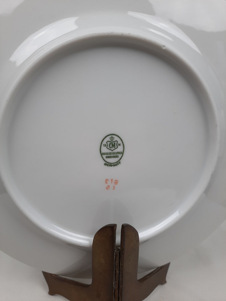 Puede incluir: Plato de porcelana blanca con un logotipo verde que dice "19 CM 14 N&Uuml;SSCHNEIDER HOF  GERMANY" y un n&uacute;mero rosa "C19 8J".