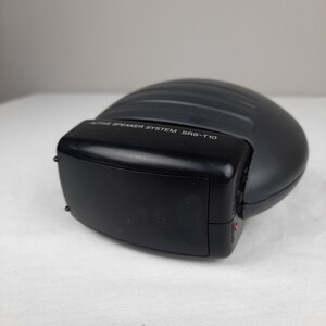 以下が含まれることがあります： 上部に「ACTIVE SPEAKER SYSTEM SRS-T10」と印刷された黒いアクティブスピーカーシステム。スピーカーは丸みを帯びた形状で、側面に黒い電源ボタンがあります。