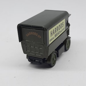 Puede incluir: Un cami&oacute;n de reparto de juguete de metal fundido en color verde oscuro con un panel lateral crema que muestra el texto HARRODS SPECIAL BREAD DELIVERY y el texto HARRODS LTD en la puerta trasera. El veh&iacute;culo tiene cuatro ruedas verdes.