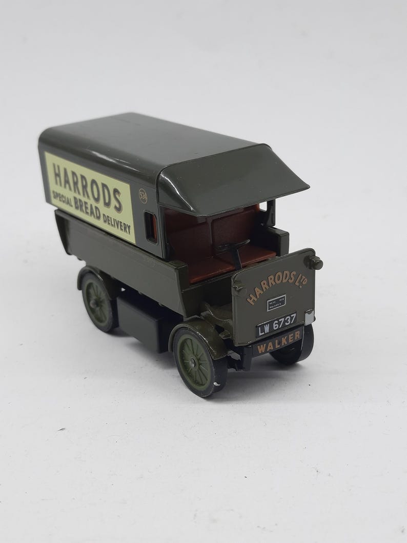 Puede incluir: Un cami&oacute;n de reparto de juguete de estilo antiguo en color verde oscuro con un panel lateral crema que presenta el texto HARRODS SPECIAL BREAD DELIVERY. El panel frontal muestra HARRODS LTD, la matr&iacute;cula LW 6737 y la palabra WALKER en negro.