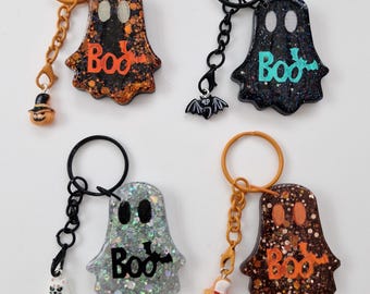 Pode incluir: Quatro porta-chaves em forma de fantasma com acabamentos brilhantes e a palavra Boo impressa na frente. Cada porta-chaves possui um anel de metal, uma corrente e um pequeno pendente, incluindo uma abóbora, um morcego, um gato branco e outra abóbora.