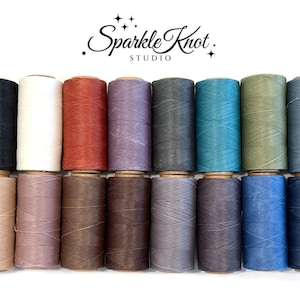 May include: Sixteen spools of thread arranged in two rows, featuring a diverse palette of colors including black, white, rust, lavender, gray, teal, olive, blue, beige, mauve, brown, and dark gray. The text Sparkle Knot STUDIO is centered above.