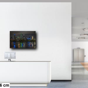 May include: A nighttime cityscape photograph of Dallas, Texas, with the city skyline reflected in the water. The buildings are illuminated with colorful lights, creating a vibrant and dynamic scene. The image is 20x30 inches or 50x76 centimeters.