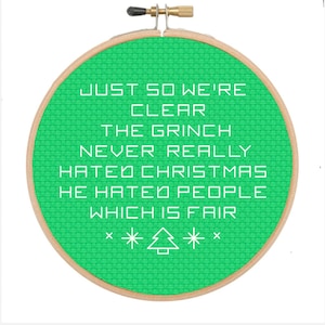 May include: A green embroidery hoop with white text that reads "JUST SO WE'RE CLEAR THE GRINCH NEVER REALLY HATED CHRISTMAS HE HATED PEOPLE WHICH IS FAIR" and a small white Christmas tree with stars on either side.