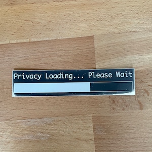 Peut inclure: Un autocollant noir et blanc avec le texte "Privacy Loading... Please Wait" et une barre de progression.