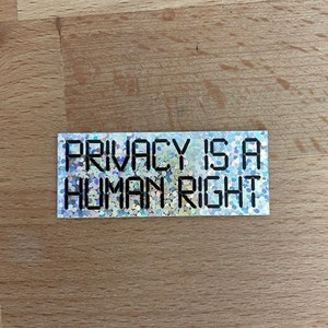 Peut inclure: Un autocollant argenté avec une finition scintillante qui dit "Privacy is a Human Right".