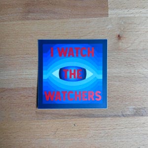 Puede incluir: Una pegatina cuadrada con un diseño de círculos concéntricos azules que se asemeja a un ojo. El texto I WATCH THE WATCHERS está impreso en letras mayúsculas rojas y negritas en el centro, con la palabra THE situada en la pupila azul oscuro.