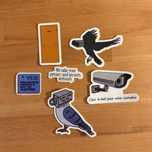 Peut inclure: Ensemble d'autocollants sur le thème de la sécurité. Comprend une porte, un corbeau avec une caméra, une caméra de sécurité, un pigeon avec une caméra et un circuit imprimé. Le texte comprend "We take your privacy and security, seriously."
