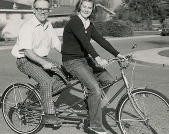 Bicycle built for two. 1960s couple on a Schwinn Twinn tandem bike. Vintage original black & white vernacular snapshot photo.