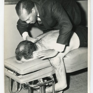 A very hairy massage. Man massaging another man. Vintage original black & white vernacular snapshot photo.