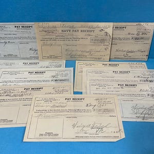 May include: A collection of ten vintage Navy pay receipts, all printed on white paper with black ink. The receipts are dated from 1943 to 1973 and show the amount of pay received by the individual. The receipts are all in good condition and have been well-preserved.