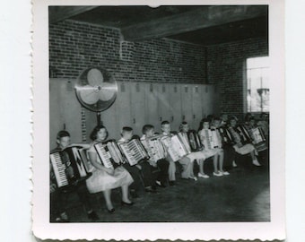 Accordion to who? Row of squeezebox youngsters in an undoubtedly noisy room. Vintage original black & white vernacular snapshot photo.