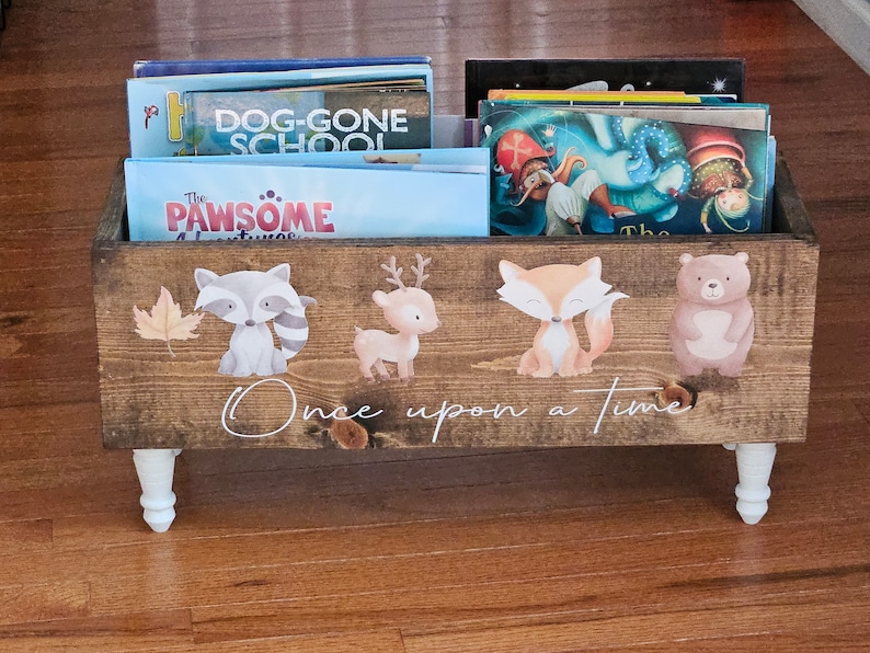 May include: Wooden bookshelf with white legs, filled with children's books. The front of the bookshelf is decorated with woodland animal illustrations and the words "Once upon a time".
