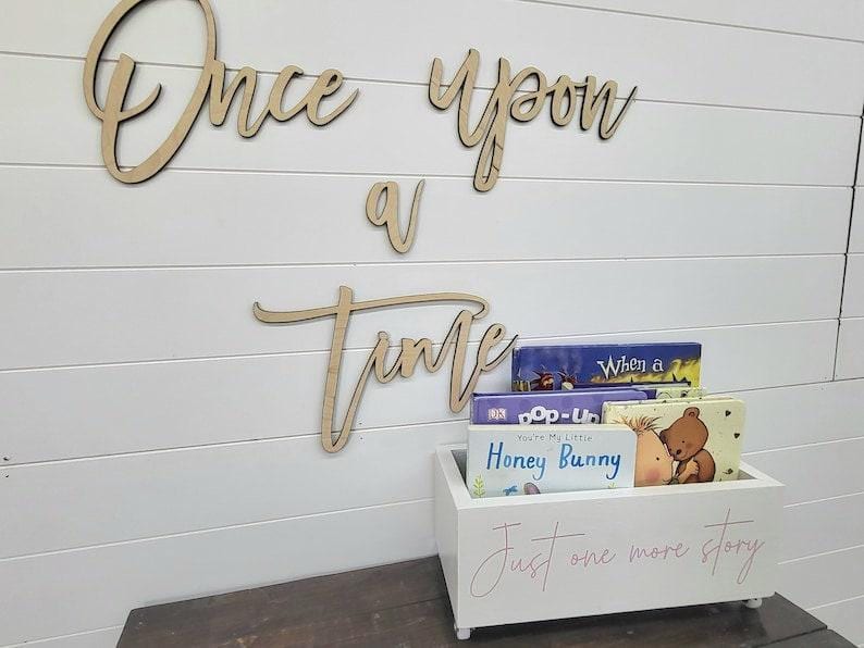 May include: Wooden sign with the words "Once upon a time" above a white box filled with children's books. The box has the text "Just one more story" in pink script.