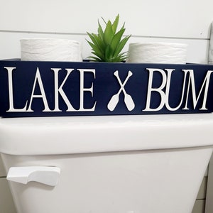 May include: A rustic wooden sign with the text "Welcome to our home" in white lettering. The sign features a distressed finish and a simple, inviting design, perfect for a front porch or entryway.
