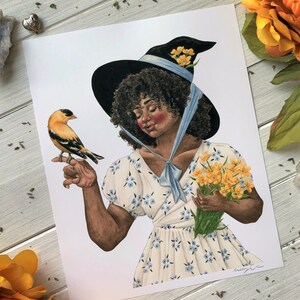 May include: A watercolor illustration of a woman with dark curly hair wearing a black witch hat with a blue ribbon and a white dress with blue flowers. She is holding a bouquet of yellow flowers and a small yellow bird is perched on her finger.