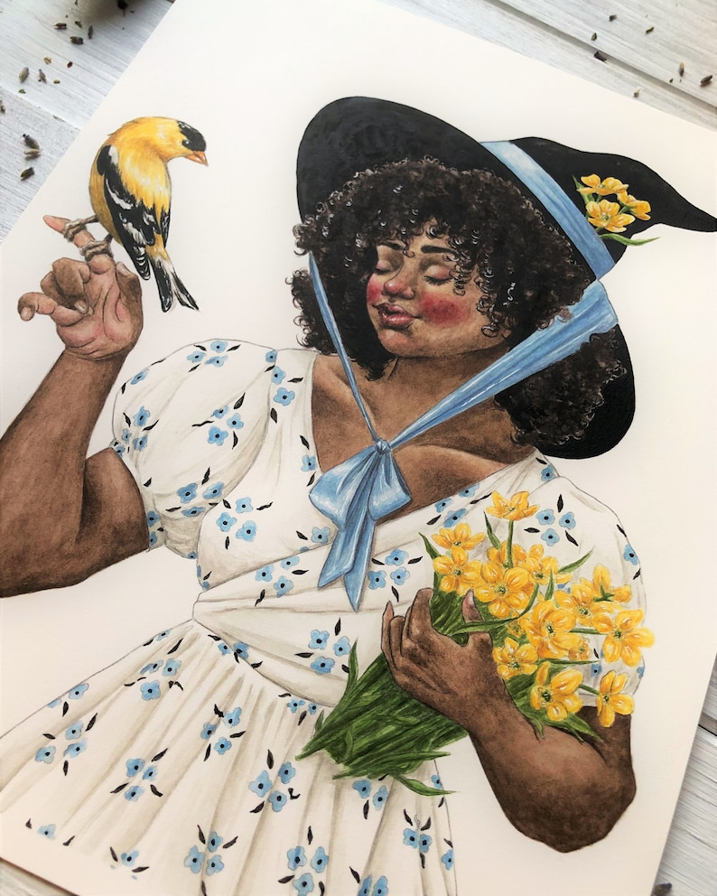 May include: A woman with dark curly hair wears a black witch hat with a blue ribbon and a white dress with blue floral print. She holds a bouquet of yellow flowers and a small yellow bird perches on her finger.