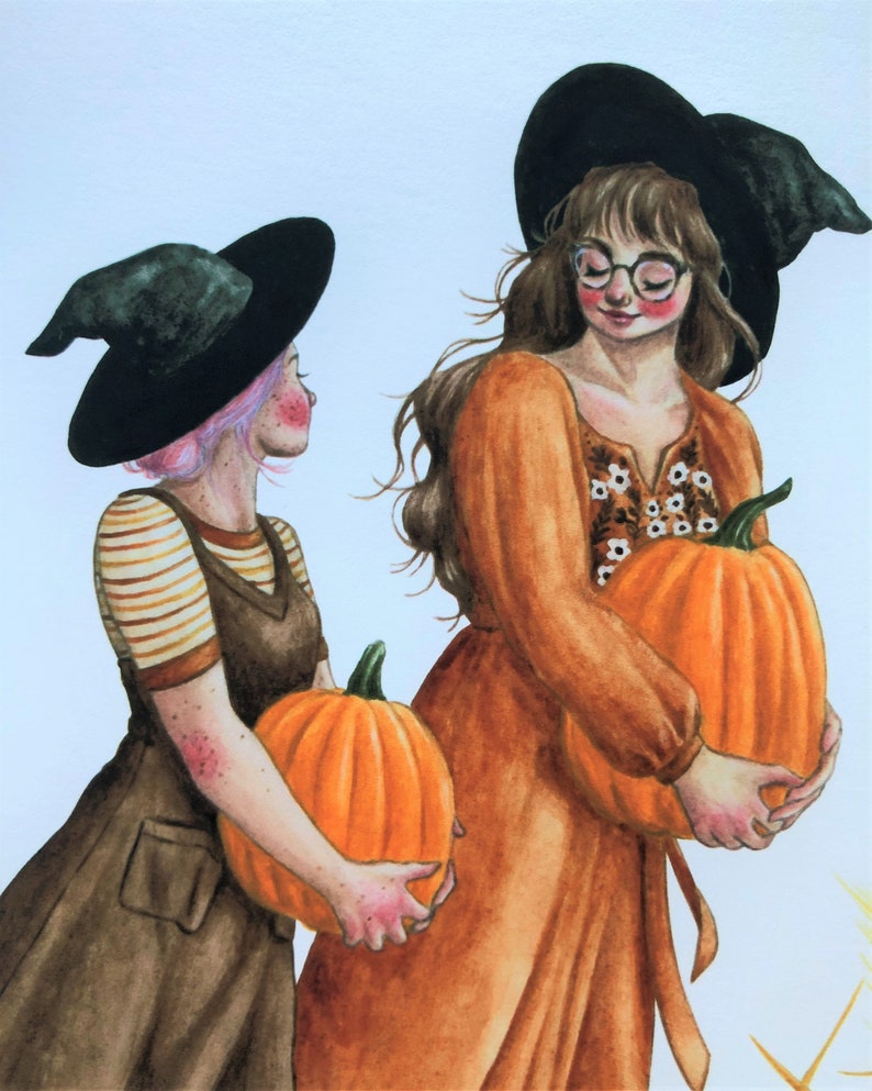 May include: Two women wearing witch hats and brown dresses hold orange pumpkins. One woman has pink hair and the other has brown hair.