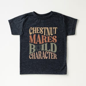 May include: A dark heather grey t-shirt with a vintage-style graphic that reads "Chestnut Mares Build Character" with a horseshoe symbol.