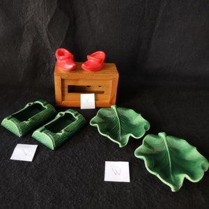 May include: A set of five ceramic trinket dishes. Two are shaped like logs, two are shaped like leaves, and one is a small wooden box with two red ceramic shoes on top.