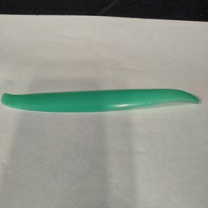 May include: A green plastic vegetable peeler with a serrated edge.