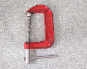 May include: A red metal C-clamp with a silver handle. The clamp has the text "SWC" printed on the side.
