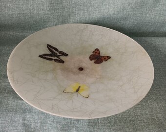 May include: A white ceramic bowl with a crackled glaze features three butterfly designs. The butterflies are brown, black, and yellow.