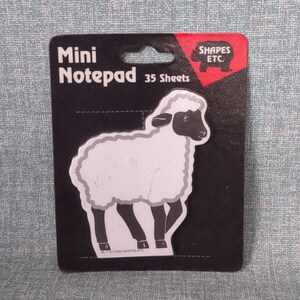 May include: A black and white mini notepad with a sheep illustration on the front. The notepad is packaged in a black and red wrapper with the text "Mini Notepad 35 Sheets" and "Shapes Etc."