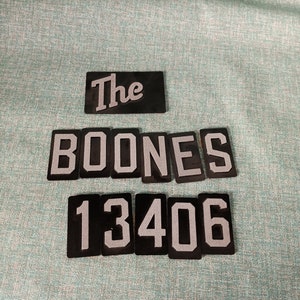 May include: Black and white plastic tiles spelling out "The Boones 13406".