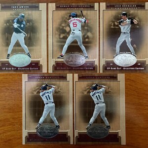 Puede incluir: Cinco tarjetas de béisbol con los jugadores Tony Gwynn, Nomar Garciaparra, Luis Gonzalez y Edgar Martinez. Cada tarjeta tiene un fondo de madera con imágenes de jugadores y texto. Las tarjetas son de la edición SP Game Bat - Milestone.